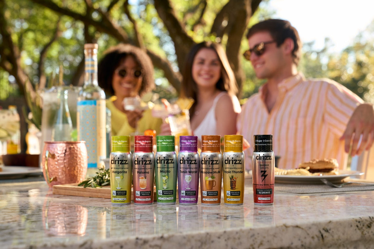 Six flavors of Drizz Mixer Drops lined up on an outdoor table
