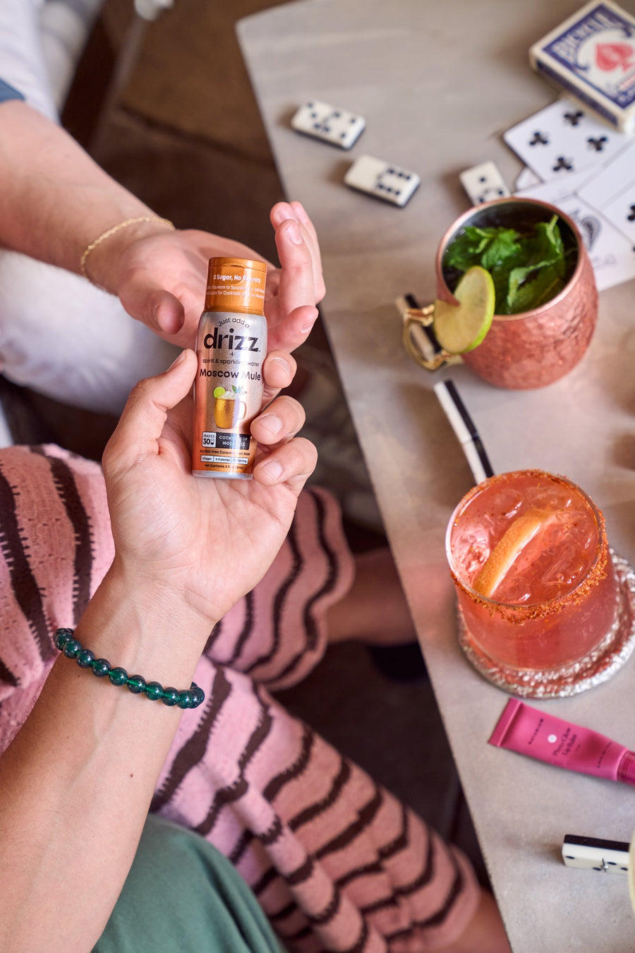 Hand squeezing a Drizz bottle at a game night table