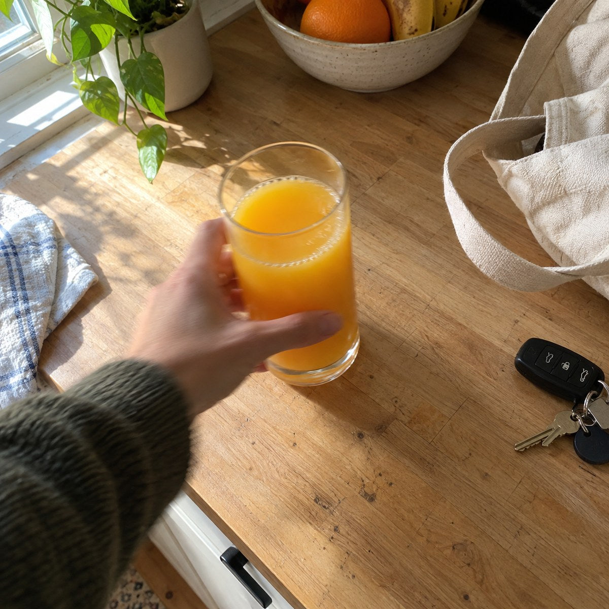 A glass of orange juice on a kitchen counter in morning light